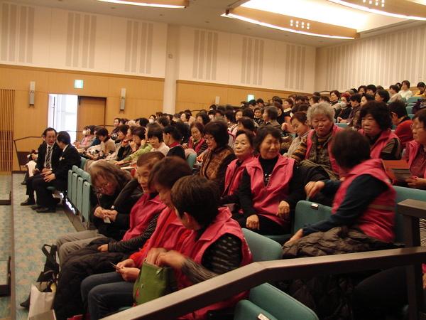 観客席にはたくさんの人が座って、席の近い人同士でお話ししている写真